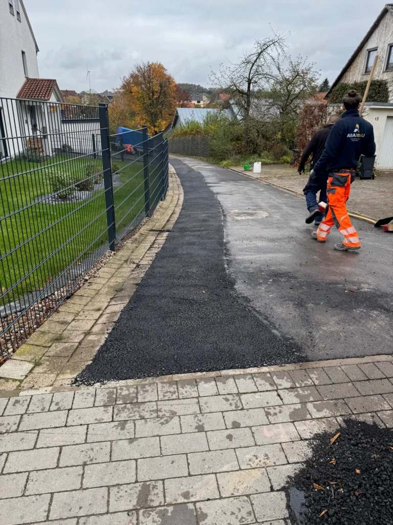 Mitarbeiter von Abazi Bau bei Asphaltarbeiten und der Wiederherstellung einer Straße nach Tiefbauarbeiten.